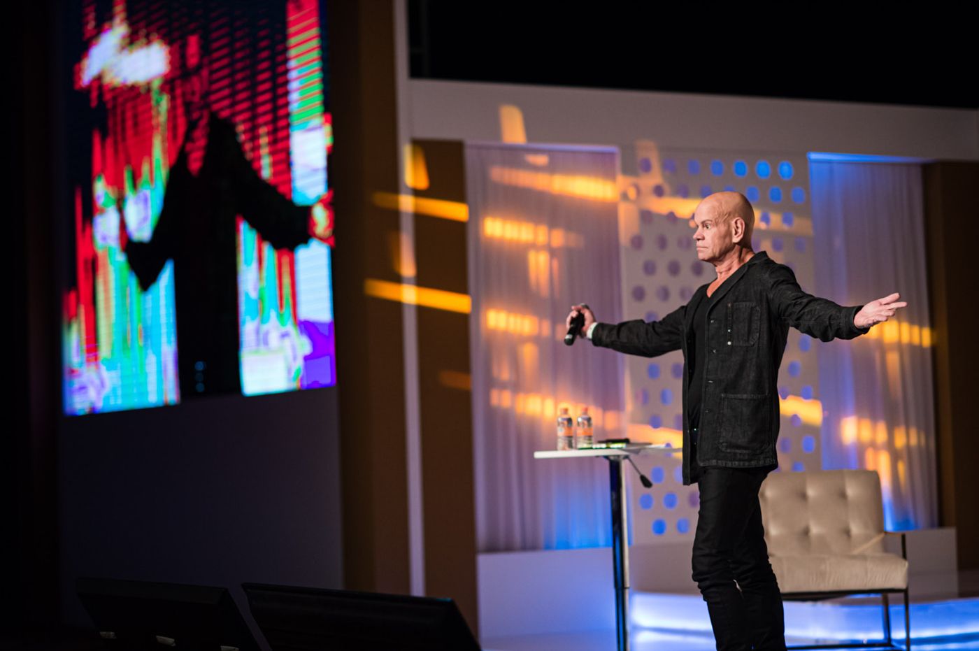 Speaker working the stage in front of the screen